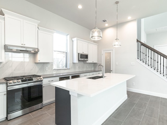 kitchen featuring pendant lighting, white cabinetry, an island with sink, and appliances with stainless steel finishes