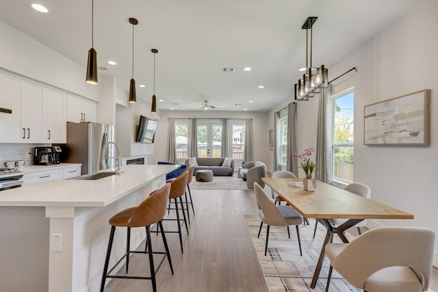 kitchen featuring white cabinets, pendant lighting, light hardwood / wood-style floors, and ceiling fan