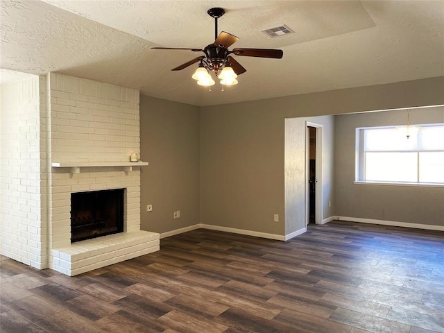 unfurnished living room with dark hardwood / wood-style flooring, ceiling fan, a fireplace, and a textured ceiling