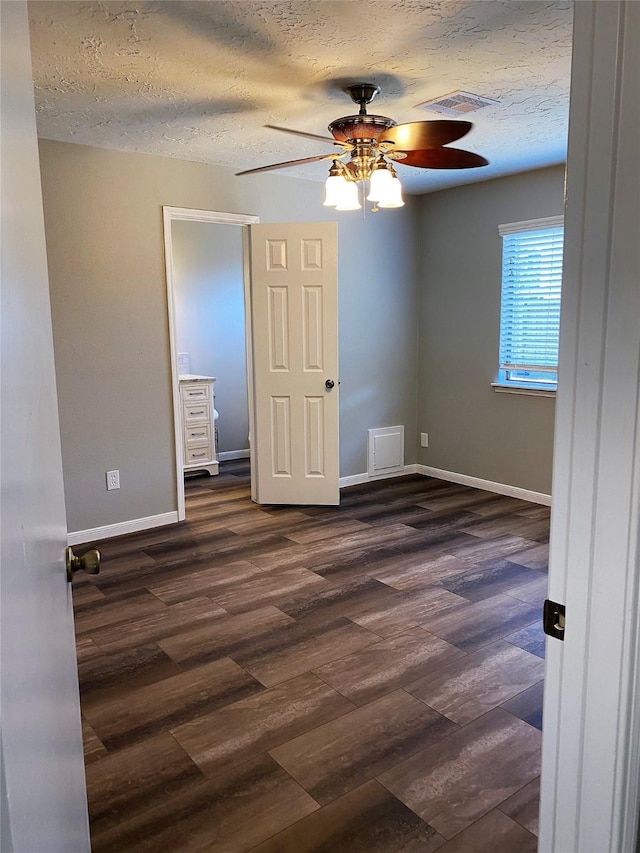 empty room with ceiling fan, dark hardwood / wood-style floors, and a textured ceiling