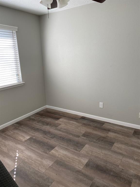 spare room with dark wood-type flooring and ceiling fan