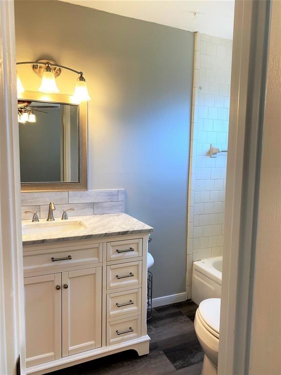 bathroom with vanity, hardwood / wood-style floors, tasteful backsplash, and toilet