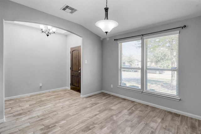 empty room featuring baseboards, visible vents, arched walkways, lofted ceiling, and light wood-type flooring