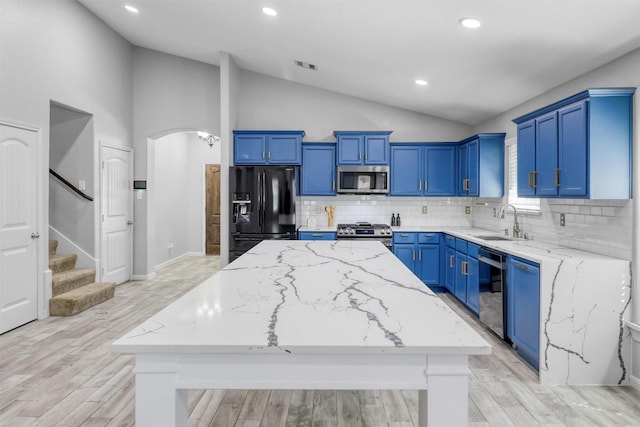 kitchen featuring a center island, backsplash, sink, vaulted ceiling, and stainless steel appliances