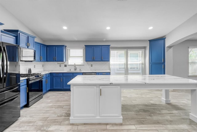 kitchen featuring blue cabinetry, light stone countertops, a center island, sink, and black appliances