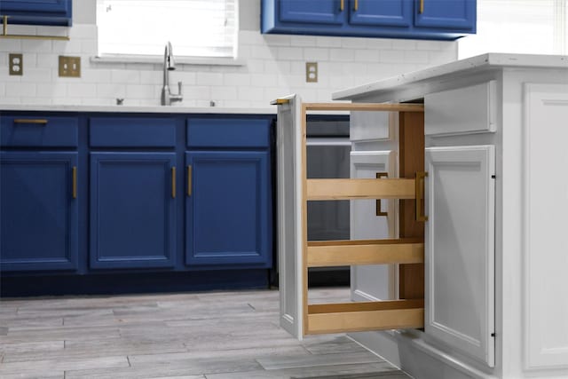 kitchen featuring light countertops, tasteful backsplash, a sink, and blue cabinets