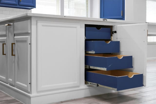 room details with hardwood / wood-style flooring, white cabinetry, and blue cabinetry