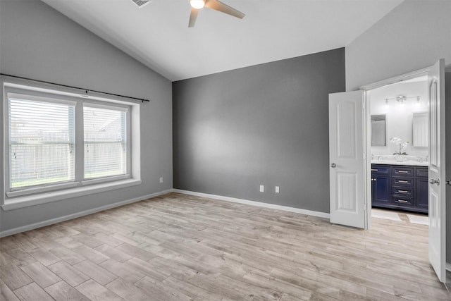 unfurnished bedroom featuring ceiling fan, light hardwood / wood-style floors, ensuite bathroom, and vaulted ceiling