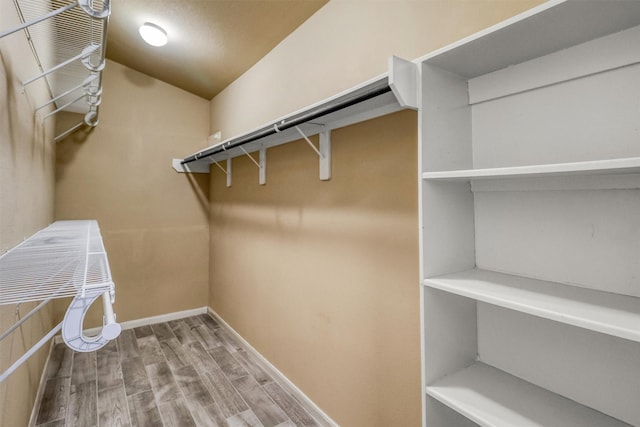 walk in closet with hardwood / wood-style flooring and vaulted ceiling