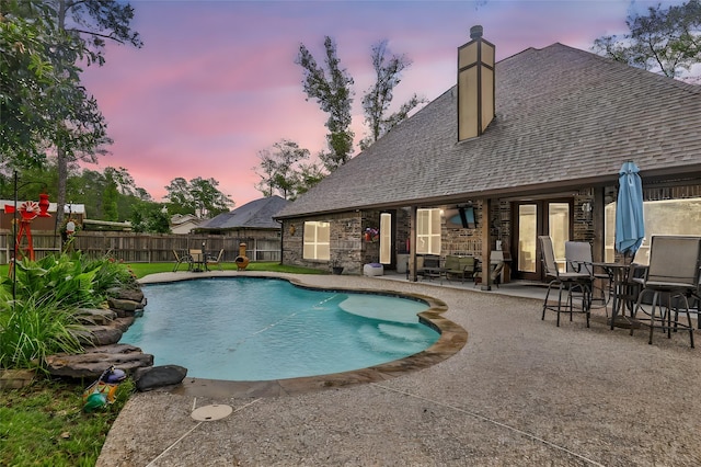 pool at dusk featuring a patio area