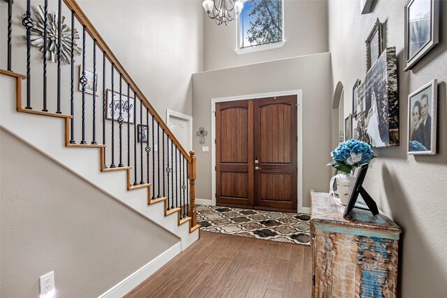 foyer featuring hardwood / wood-style flooring, a towering ceiling, and a chandelier