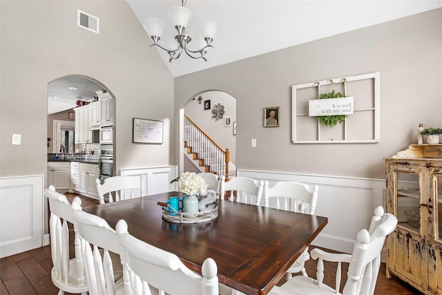 dining space with dark wood-type flooring, a chandelier, vaulted ceiling, and sink