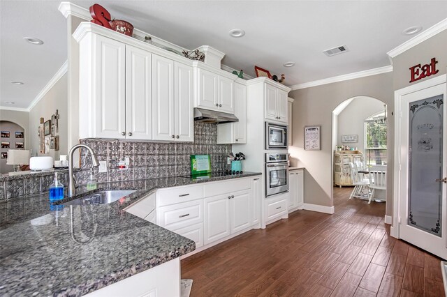 kitchen featuring sink, stainless steel appliances, tasteful backsplash, dark stone counters, and white cabinets