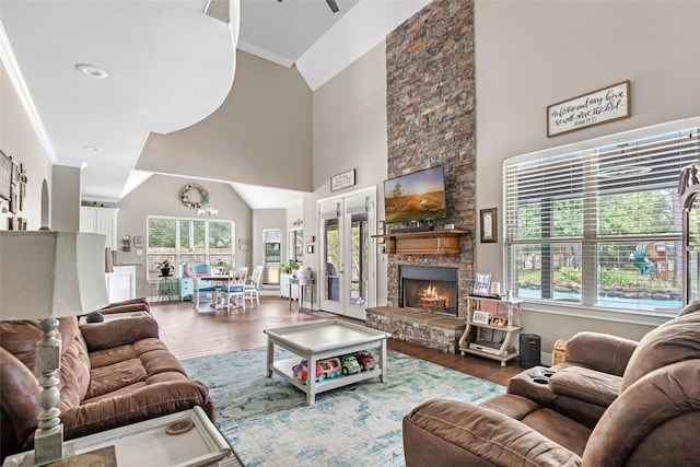 living room with a stone fireplace, hardwood / wood-style floors, french doors, and ornamental molding