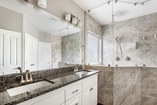 bathroom with tiled shower, vanity, and tile walls