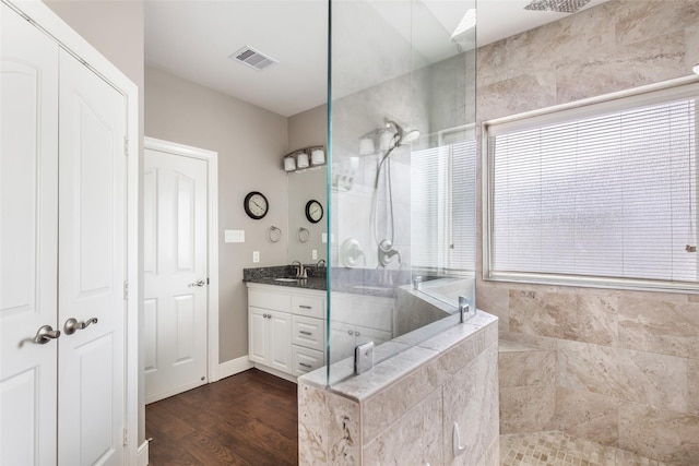 bathroom featuring a tile shower, vanity, and wood-type flooring