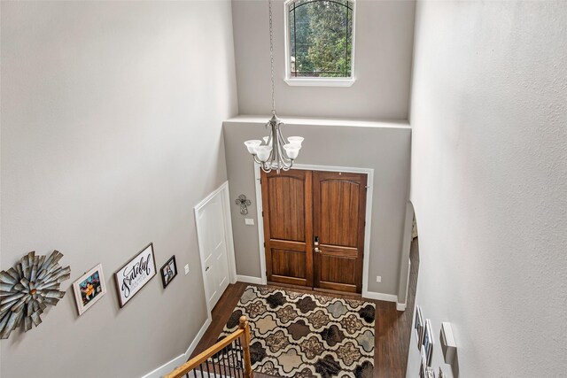 foyer with a towering ceiling, dark hardwood / wood-style flooring, and an inviting chandelier