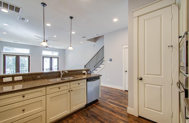 kitchen featuring french doors, appliances with stainless steel finishes, sink, dark stone countertops, and hanging light fixtures