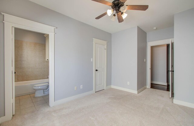 unfurnished bedroom featuring light carpet, connected bathroom, and ceiling fan