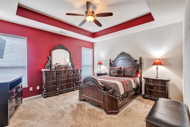 carpeted bedroom featuring a raised ceiling and ceiling fan