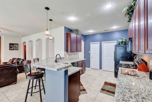 kitchen featuring light tile patterned floors, tasteful backsplash, decorative light fixtures, a kitchen bar, and kitchen peninsula