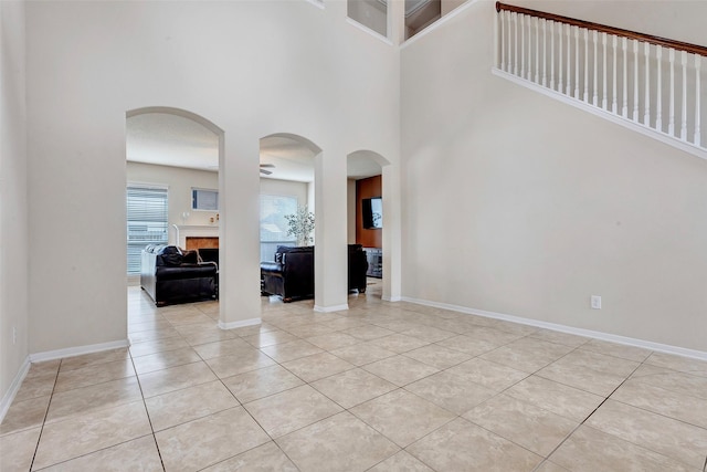 entryway with light tile patterned floors, a high ceiling, and a tiled fireplace