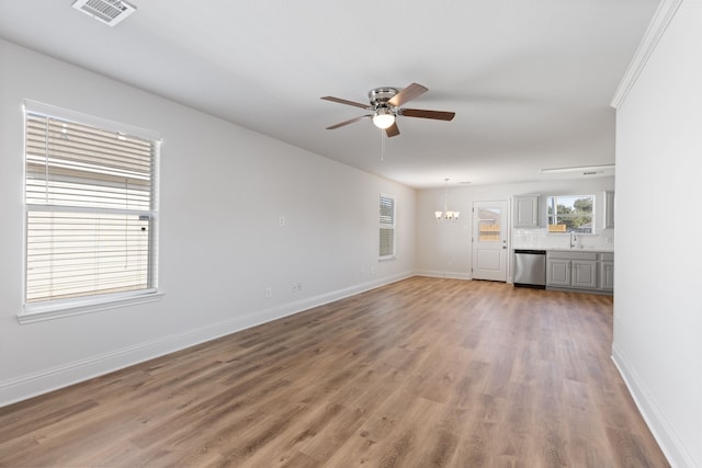 unfurnished living room featuring hardwood / wood-style floors, ceiling fan with notable chandelier, and sink