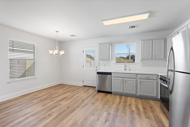 kitchen featuring gray cabinetry, a chandelier, stainless steel appliances, and tasteful backsplash