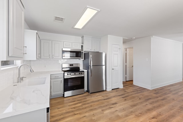 kitchen featuring light stone counters, sink, white cabinets, and stainless steel appliances