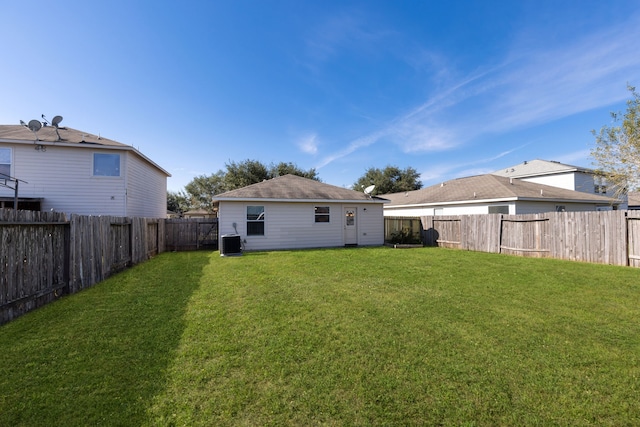 rear view of property featuring a yard and central AC unit