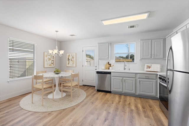 kitchen featuring tasteful backsplash, gray cabinets, a chandelier, and stainless steel appliances