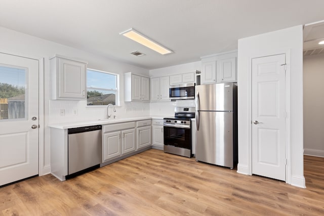 kitchen featuring backsplash, stainless steel appliances, light hardwood / wood-style floors, and sink