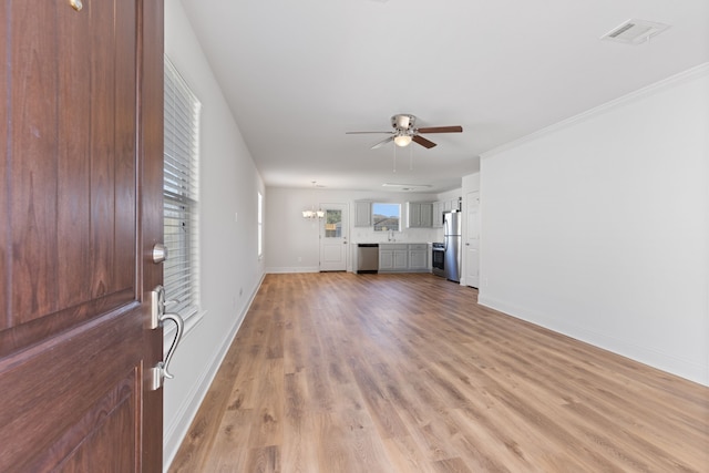 unfurnished living room featuring ceiling fan with notable chandelier, light hardwood / wood-style floors, and ornamental molding