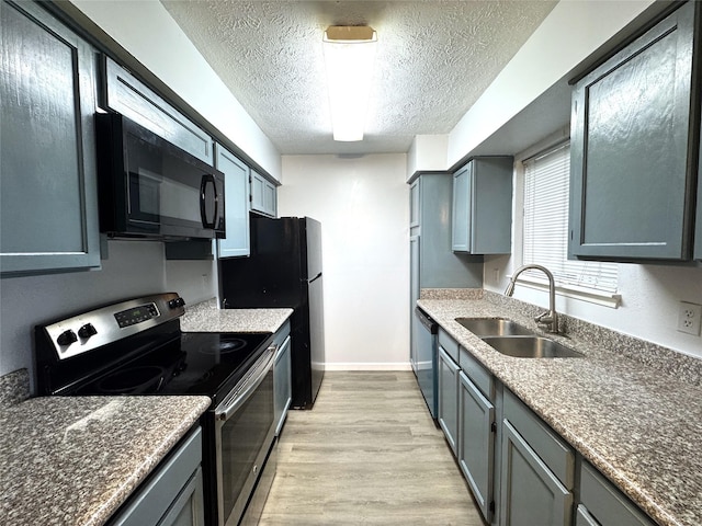 kitchen with sink, light hardwood / wood-style floors, a textured ceiling, gray cabinets, and black appliances