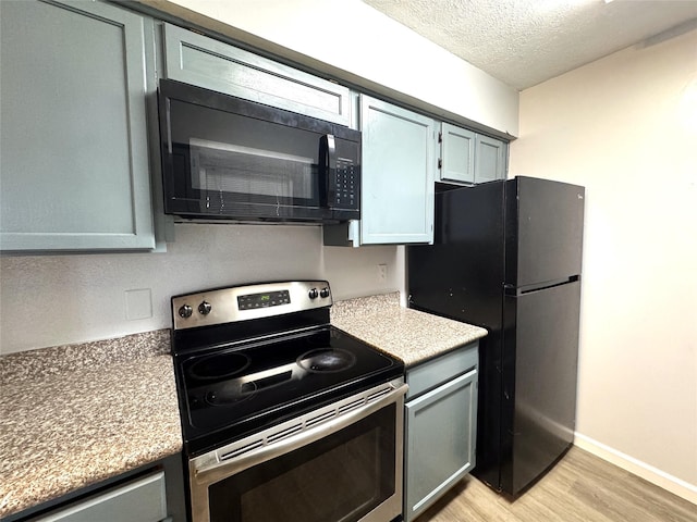 kitchen with light hardwood / wood-style floors, stainless steel electric range oven, a textured ceiling, and fridge