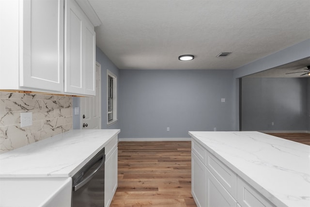 kitchen featuring white cabinets, light hardwood / wood-style flooring, light stone countertops, black dishwasher, and tasteful backsplash