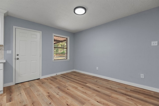 spare room with light hardwood / wood-style floors and a textured ceiling