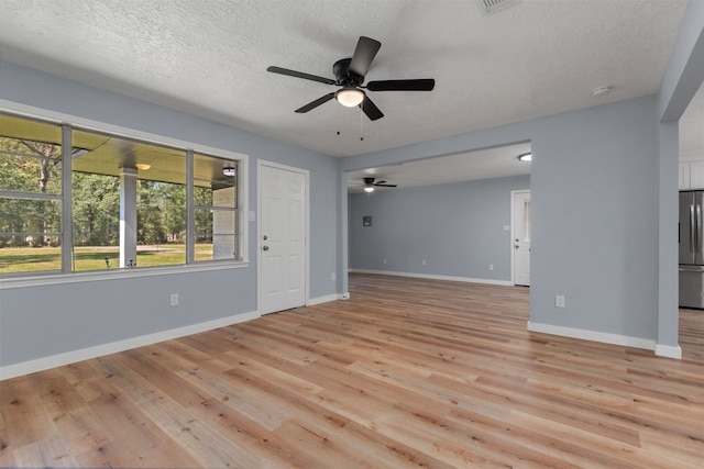 unfurnished living room featuring ceiling fan, light hardwood / wood-style floors, and a textured ceiling