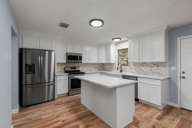 kitchen featuring white cabinets, a center island, sink, and appliances with stainless steel finishes