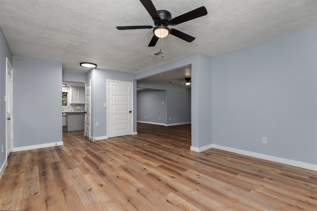 unfurnished living room with a textured ceiling, light hardwood / wood-style flooring, and ceiling fan