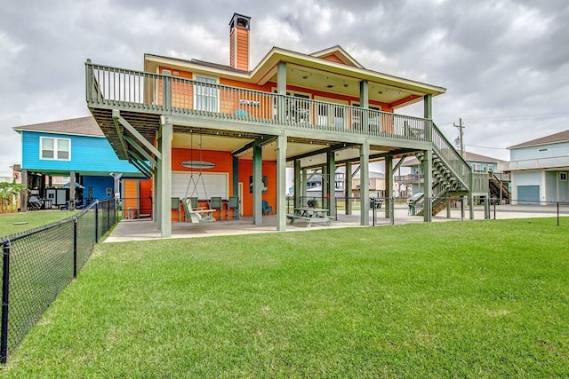 back of house featuring a lawn, a patio area, and a wooden deck