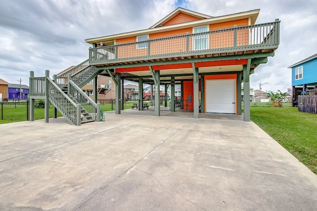 beach home with a deck, a front yard, and a garage