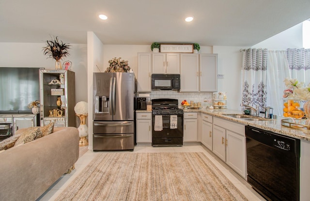 kitchen featuring light stone countertops, sink, black appliances, light tile patterned floors, and white cabinets