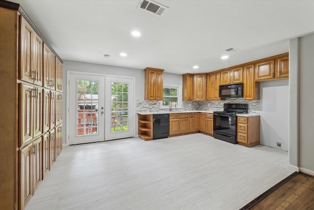 kitchen with french doors, black appliances, sink, decorative backsplash, and light hardwood / wood-style floors