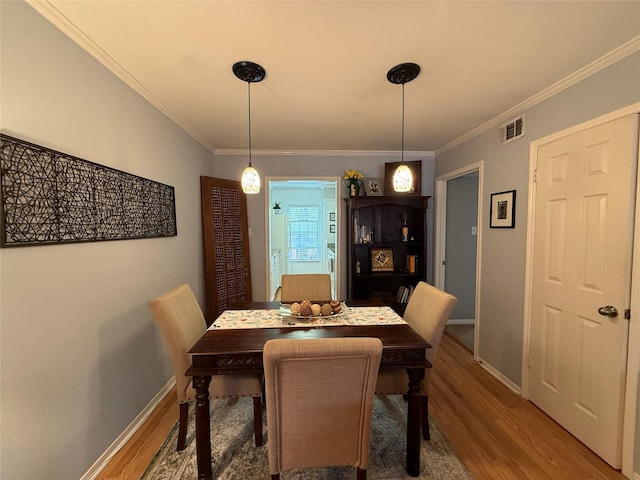 dining space featuring hardwood / wood-style floors and crown molding