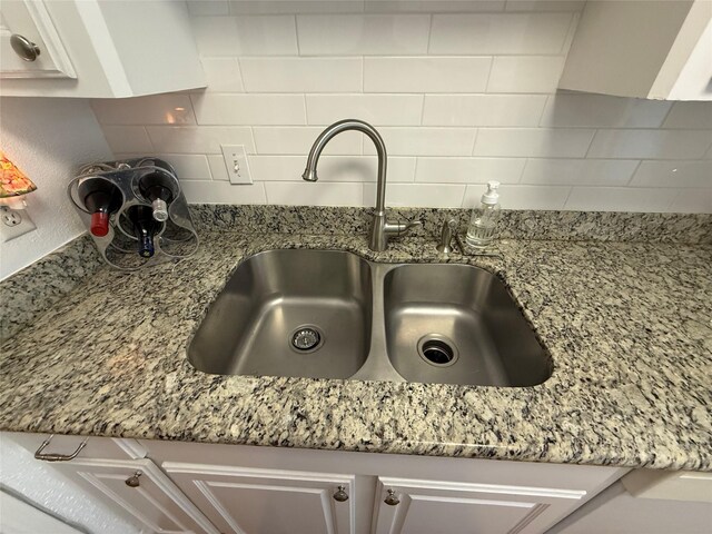 room details with decorative backsplash, stone countertops, and sink