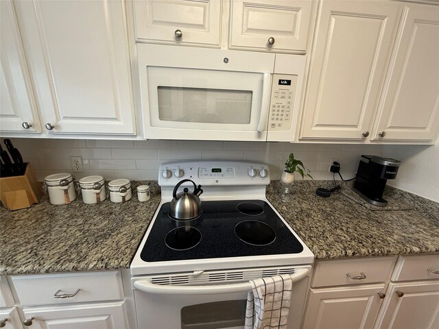 kitchen featuring white appliances, tasteful backsplash, white cabinetry, and dark stone counters