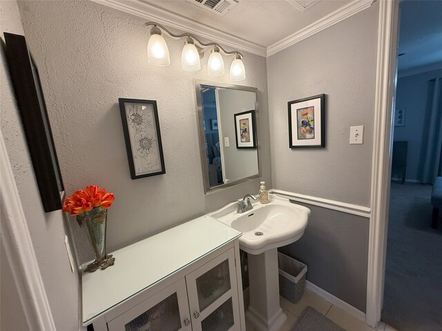 bathroom featuring tile patterned flooring, crown molding, and sink