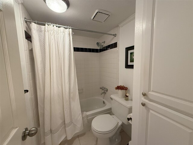 bathroom featuring tile patterned flooring, toilet, and shower / bathtub combination with curtain