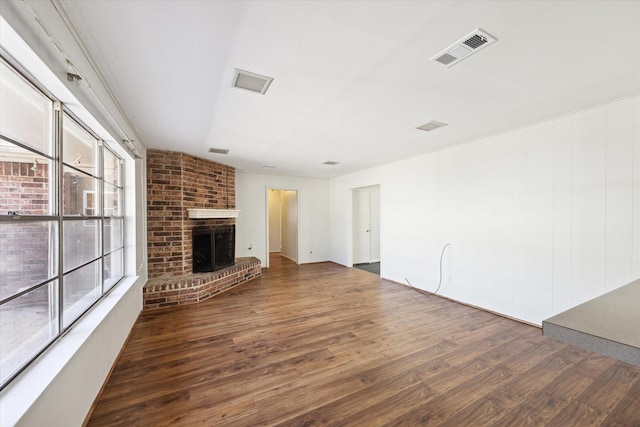 unfurnished living room with dark hardwood / wood-style flooring, a wealth of natural light, and a brick fireplace